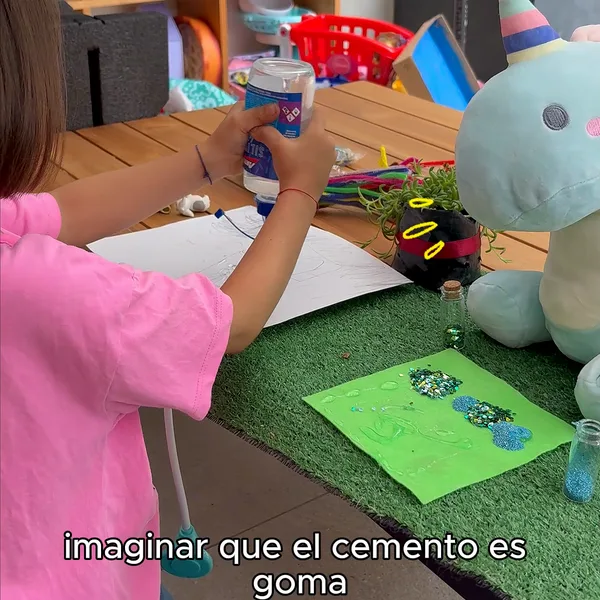 Niña de espaldas creando una maqueta junto a Nebu Unicornio