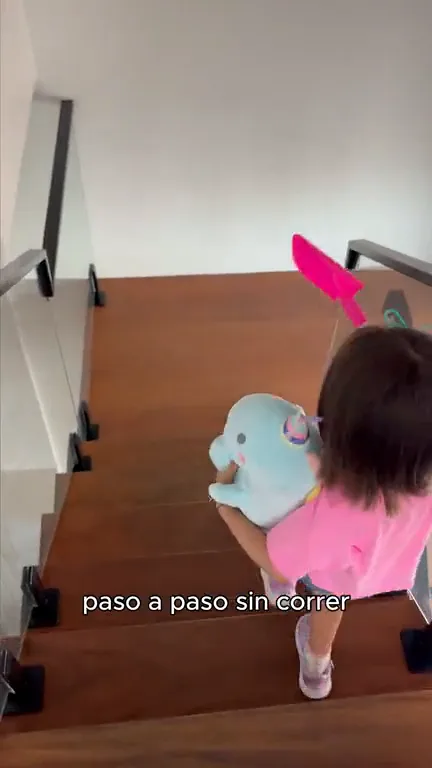 Niña de espaldas bajando las escaleras con Nebu Unicornio